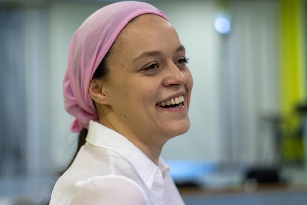 Closeup of a smiling woman wearing a pink scarf in reference to cancer