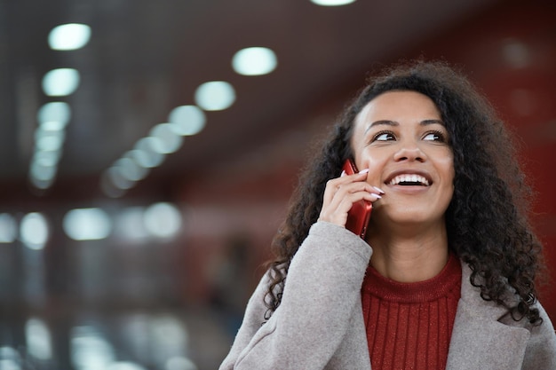 Giovane donna sorridente del primo piano con uno smartphone