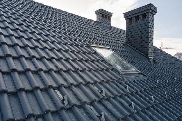 Closeup snow guard for safety in winter on house roof top covered with ceramic shingles Tiled covering of building