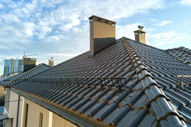 Closeup snow guard for safety in winter on house roof top covered with ceramic shingles Tiled covering of building