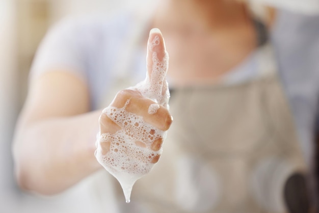 Closeup soap and person with thumbs up foam and hygiene with healthy habits agreement and wellness Zoom woman and girl with hand gesture promotion or daily care with bacteria clean and bubbles