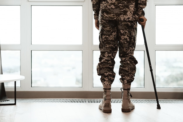 Closeup Soldiers Legs Leaning on Crutch By Window.