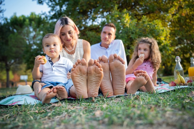 Closeup of the soles of the feet of a family during a picnic in\
a park