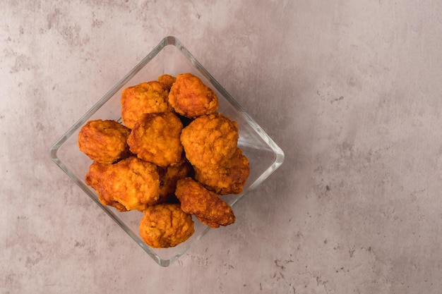 Closeup of some chicken nuggets in a glass dish on a table ready to eat