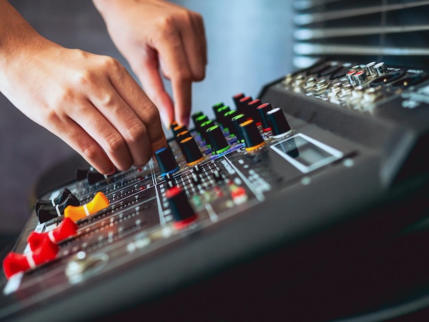 Foto close-up delle mani dell'ingegnere del suono che regolano il mixer di controllo del suono nella registrazione della verifica del suono della trasmissione