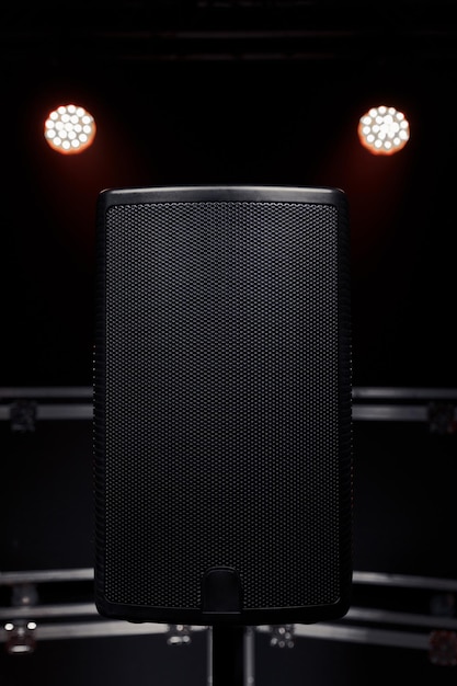 Closeup of a sound speaker against the background of concert\
lighting