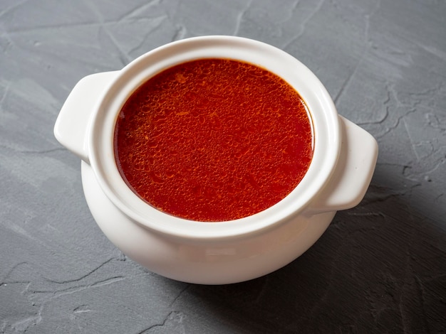 Closeup of soup borscht in a white ceramic soup bowl on a gray textured background Traditional soup for Russia and Ukraine