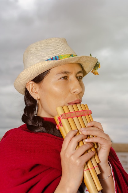 サンポナを演奏する帽子をかぶった南米先住民女性のクローズアップ