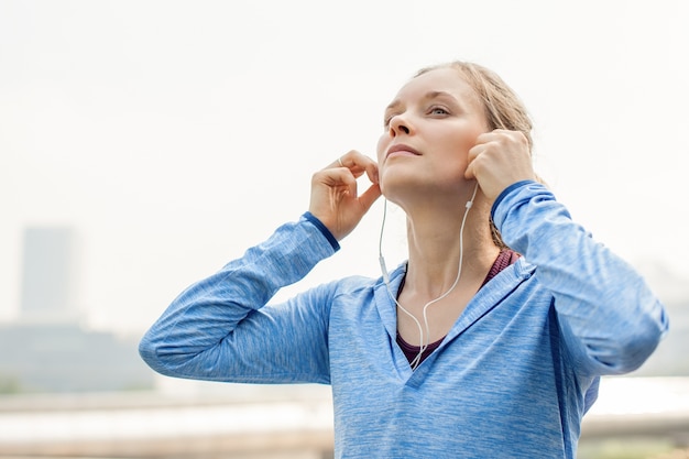 Photo closeup of sporty girl listening to music in city