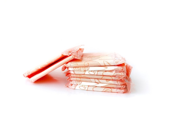 Closeup Stack of women's sanitary napkins individually wrapped in pink on white. Critical days, mens