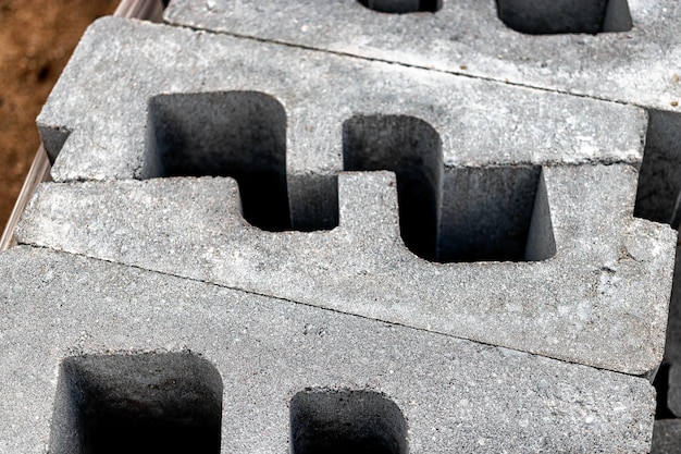 Closeup of stacked hollow gray concrete bricks or blocks from a construction site