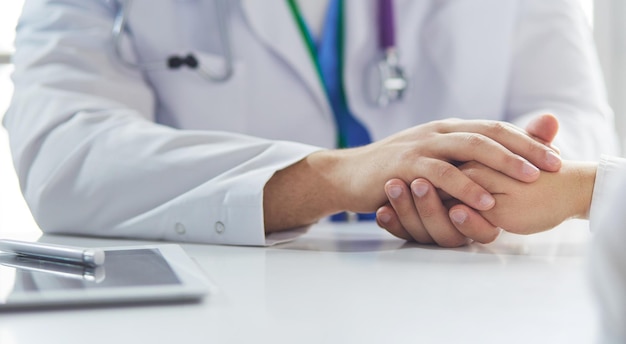 Closeup of stethoscope and paper on background of doctor and patient hands