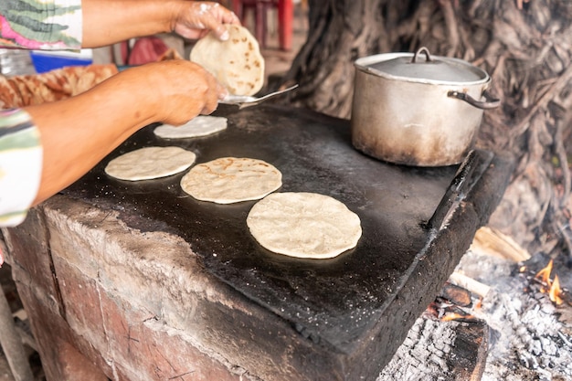 Closeup to the stove with a metal plate in which tortillas are being cooked