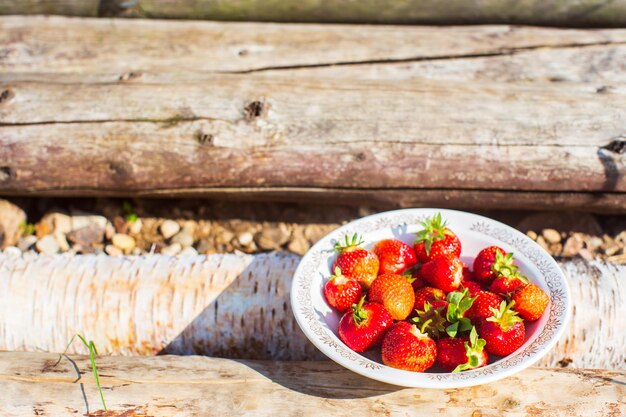 사진 농촌의 나무 계단 위에 접시에 놓인 딸기 작물 건강한 음식 비타민 농업 시장 딸기 판매의 개념