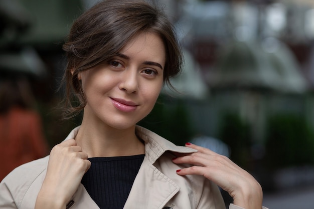 Closeup street portrait of a beautiful brunette tanned woman with nude makeup and short hair walking at the street. Space for text