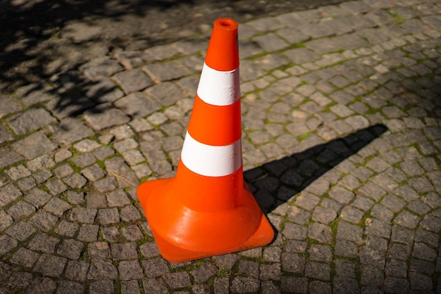 Closeup of striped orange and white road cone on pavement Bright orange traffic cone for parking in the street