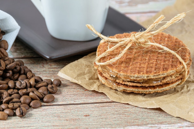 Closeup of stroopwafel biscuits with a sisal bow next to coffee beans.