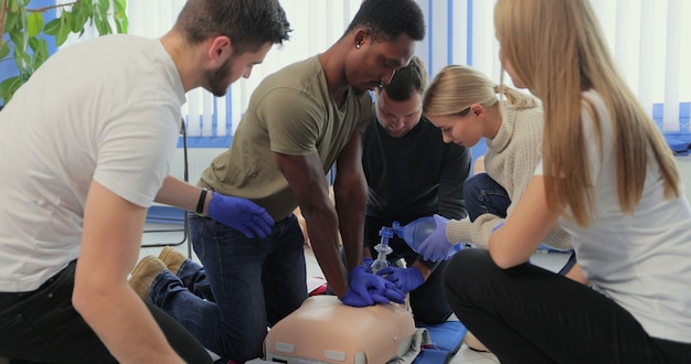 Photo closeup of students practicing cpr chest compression on dummy.
