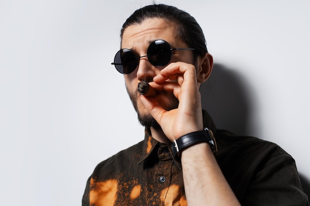 Closeup studio portrait of young man with a cigar on white background