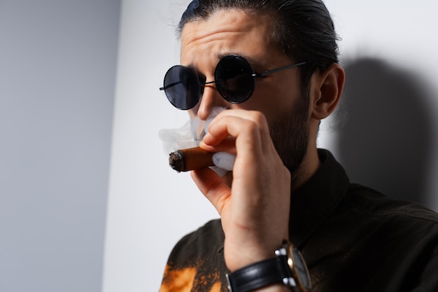 Closeup studio portrait of young man with a cigar on white background