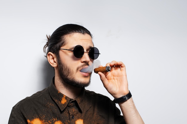 Closeup studio portrait of young man with a cigar on white background