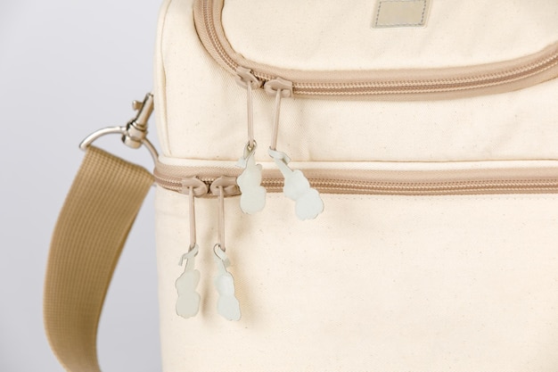 Photo closeup studio shot of cream and beige color multifunction multipurpose utility compartments zipper newborn baby toddler mommy bag with handle and long durable adjustable strap on white background