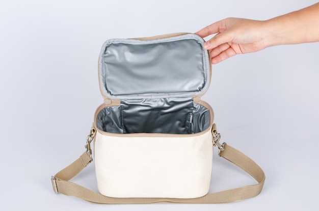 Photo closeup studio shot of hand opening showing inside compartments of multifunction multipurpose hot and cold temperature control baby toddler mommy bag with long adjustable strap on white background