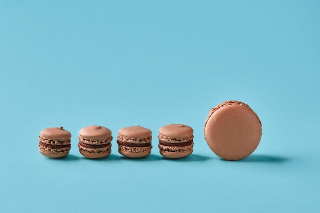 Colpo dello studio del primo piano di gustosi macarons al cioccolato su sfondo blu