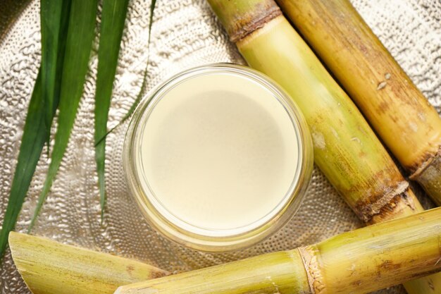 Closeup of sugarcane and fresh cane juice in a metal tray top view