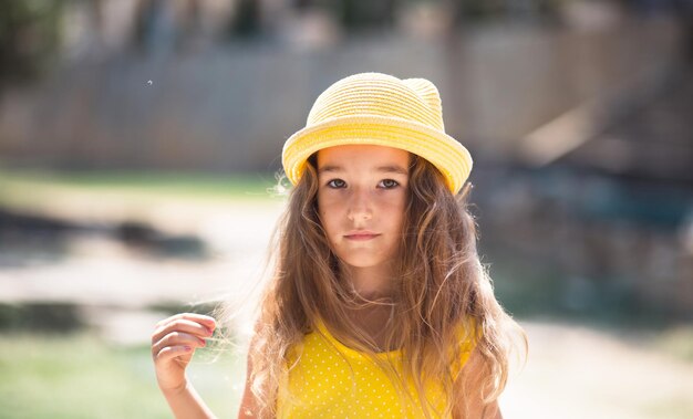 Closeup of a summer portrait of a girl in a yellow hat and sundress Sunny summer time freedom