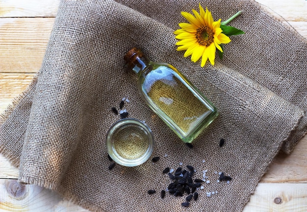 Closeup of sunflower oil in a bottle glass with seeds on burlap canvas fabric background Top view