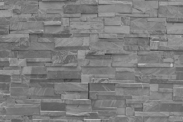 Closeup surface brick pattern at old black stone brick wall textured background in black and white tone