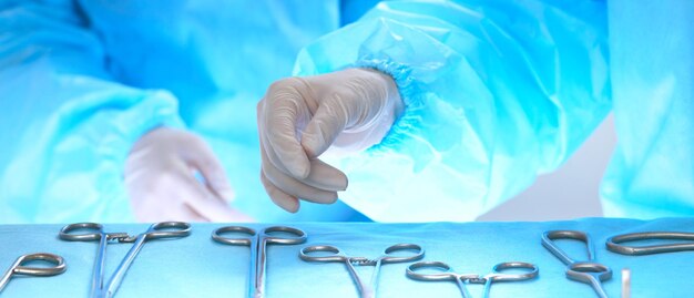 파란색으로 톤된 수술실에서 일하는 외과의사 손 클로즈업