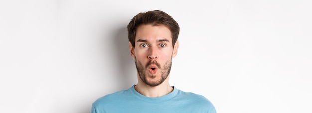 Photo closeup of surprised man face saying wow and staring at camera amazed standing on white background