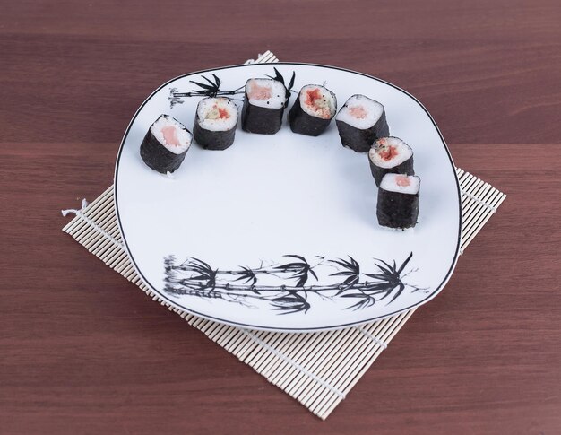 Primo piano di sushi e bacchette su un piatto bianco