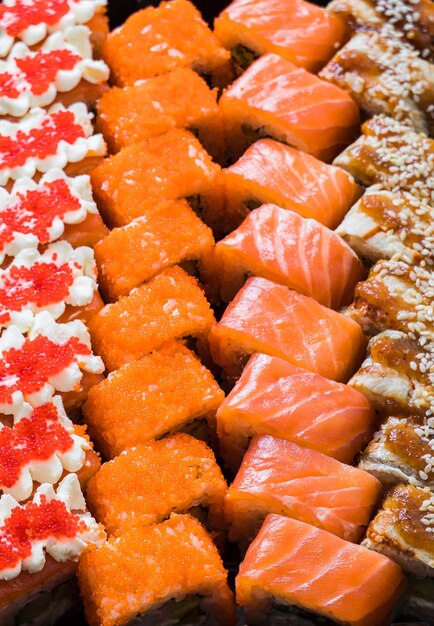 Closeup of sushi rolls of different kinds cut into slices and laid out in a row