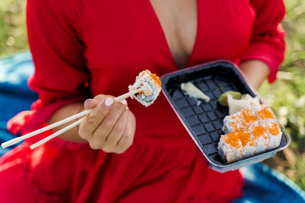 Closeup sushi set food delivery. Sexy girl holds sushi with chopsticks in hands. 