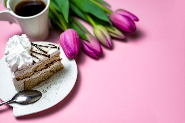 Primo piano dolce torta al caffè nero e tulipani lilla su sfondo rosa chiaro primo piano biglietto di auguri con spazio per la copia del testo