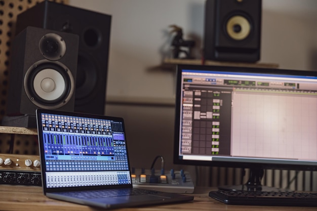 Closeup of switched on laptop and monitor screen on table in broadcasting and recording studio