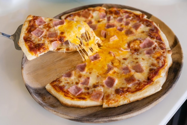 Closeup taking piece of pizza Cheese pizza with ham slices Home and office delivery concept