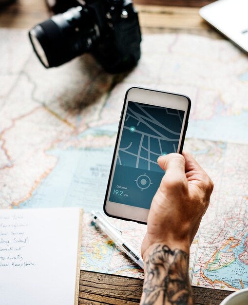 Photo closeup of tattoo hand holding mobile phone showing gps route