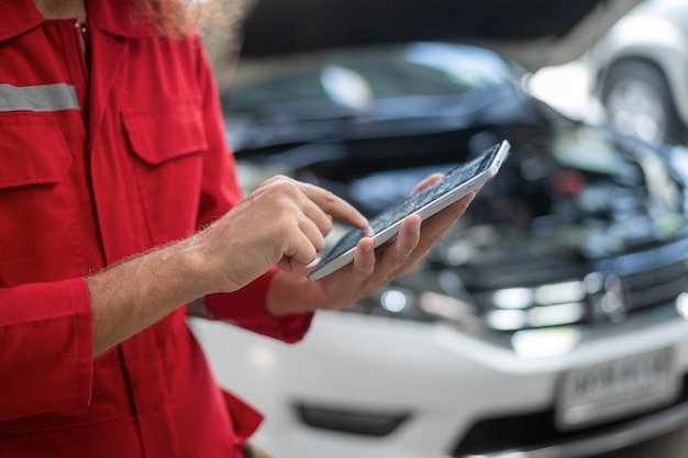 Closeup technician man hand using tablet analyzing car problems in auto repair shop