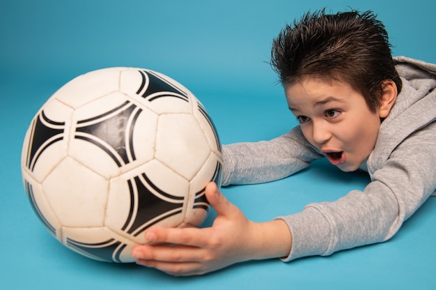 Photo closeup of a teenage boy, goalkeeper, catching a soccer ball, lying on the floor