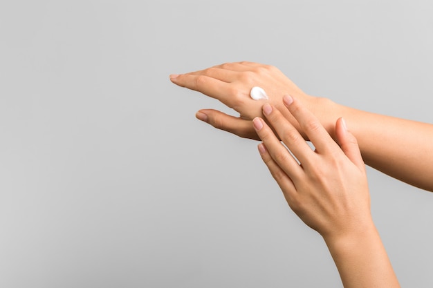 Closeup of tender hands of a young woman with moisturizer on. spring skin protection