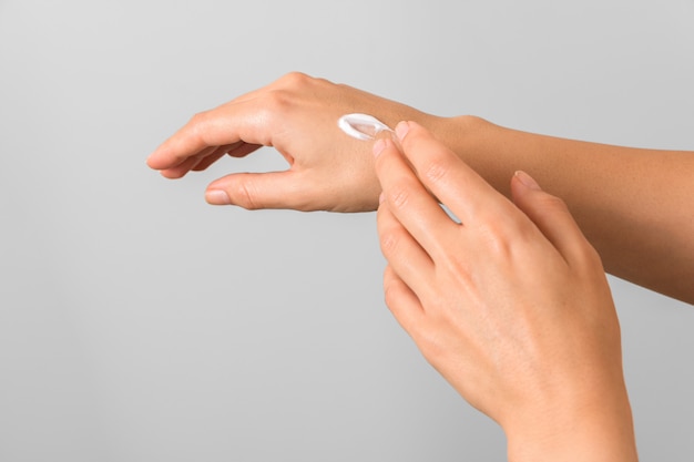 Photo closeup of tender hands of a young woman with moisturizer on. spring skin protection