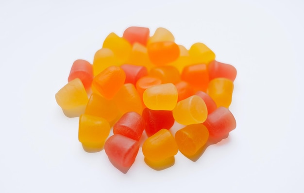 Closeup texture of orange and yellow multivitamin gummies in the form of bears on white background