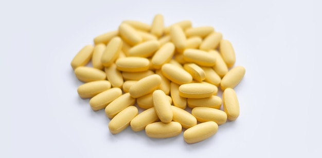 Closeup texture of yellow multivitamin tablets on white background Healthy lifestyle concept