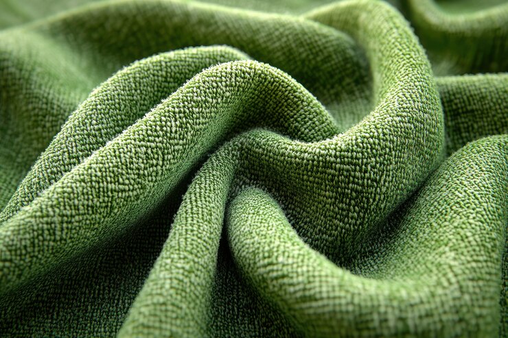 Photo closeup of a textured green fabric showcasing intricate folds and soft fibers ideal for textile design