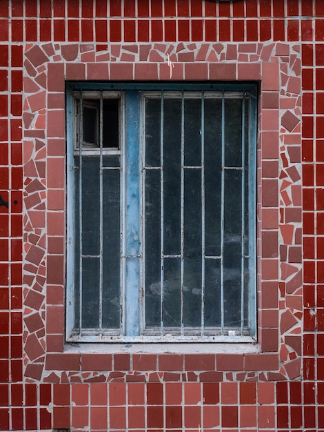 Photo closeup of a textured old wooden window in a wall with red ceramic tiles on the wall of an old soviet typical panel socialist apartment building soviet modernism architecture