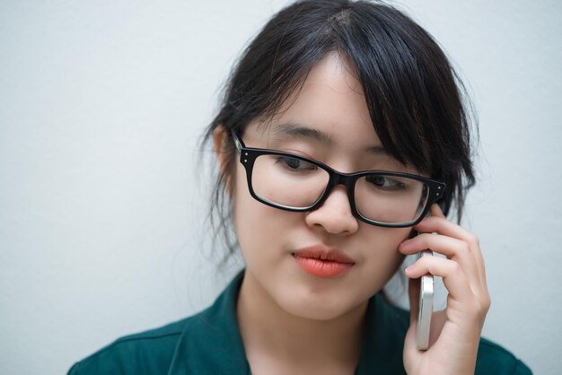 Closeup thaise vrouw gebruikt smartphone op witte muur Aziatisch meisje belt telefoon voor werk Praten op mobiele telefoon